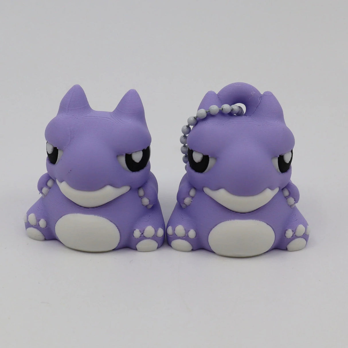 Two purple 3D printed warthog sensory toys with white accents and a keychain on one