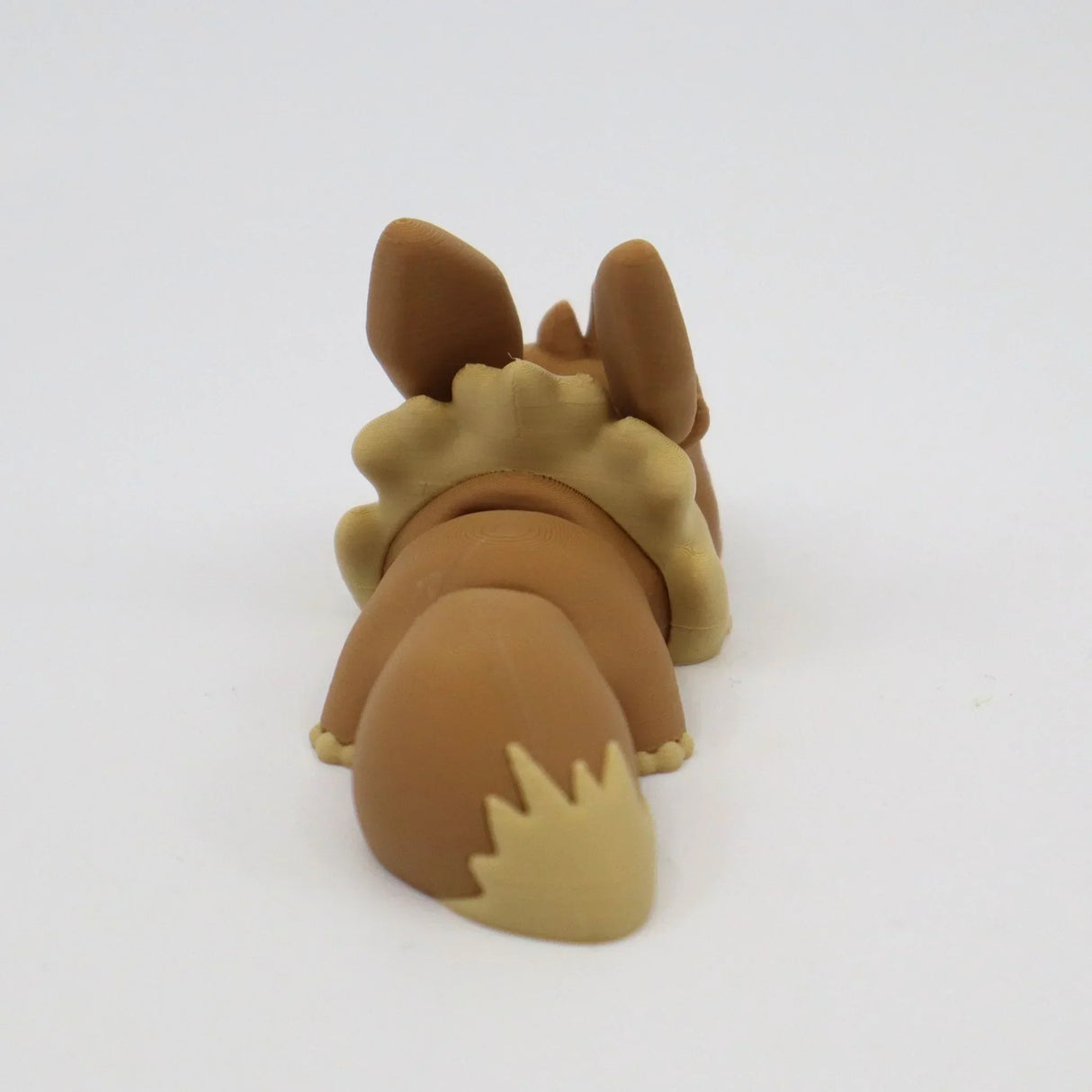 3D printed brown sensory toy shaped like a dog laying down, shown from behind