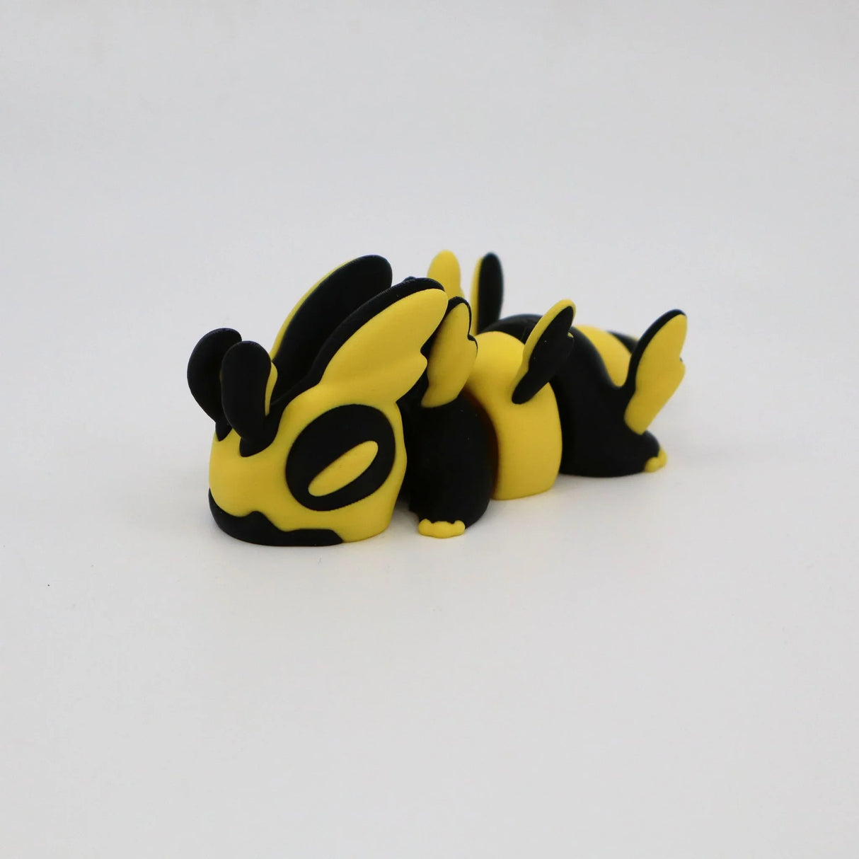 Yellow and black 3D printed sensory toy, shaped like a playful animal, on white background.