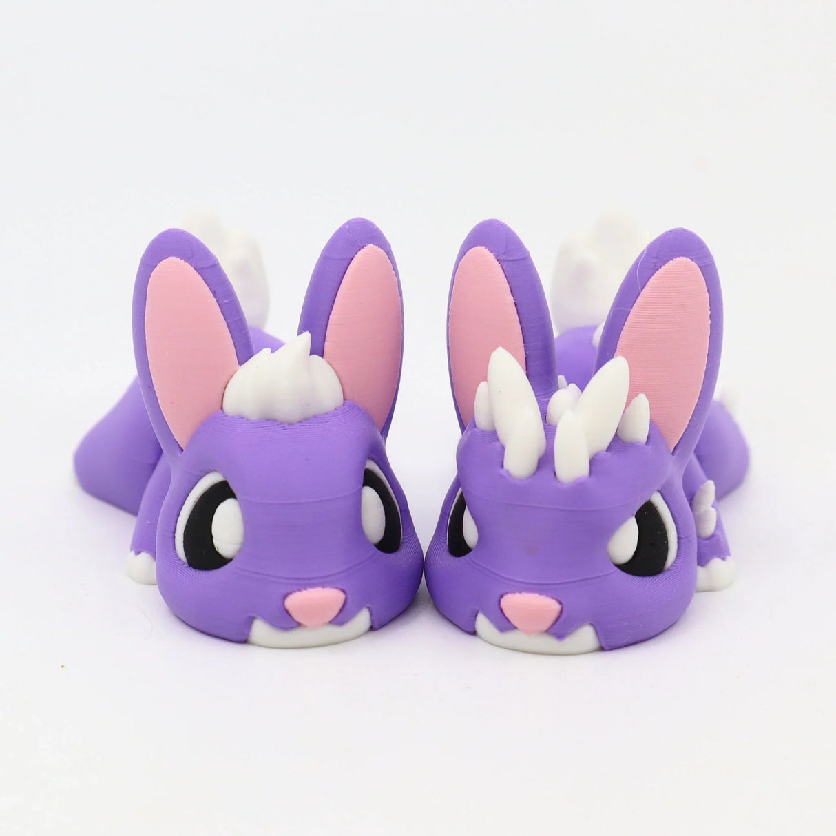 Two purple 3D printed sensory bunny toys with white spikes and pink details on a white background.
