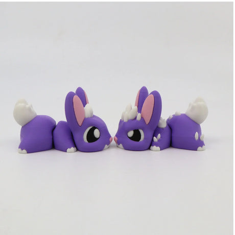 Two purple 3D printed bunny sensory toys with white tails and pink ears facing each other