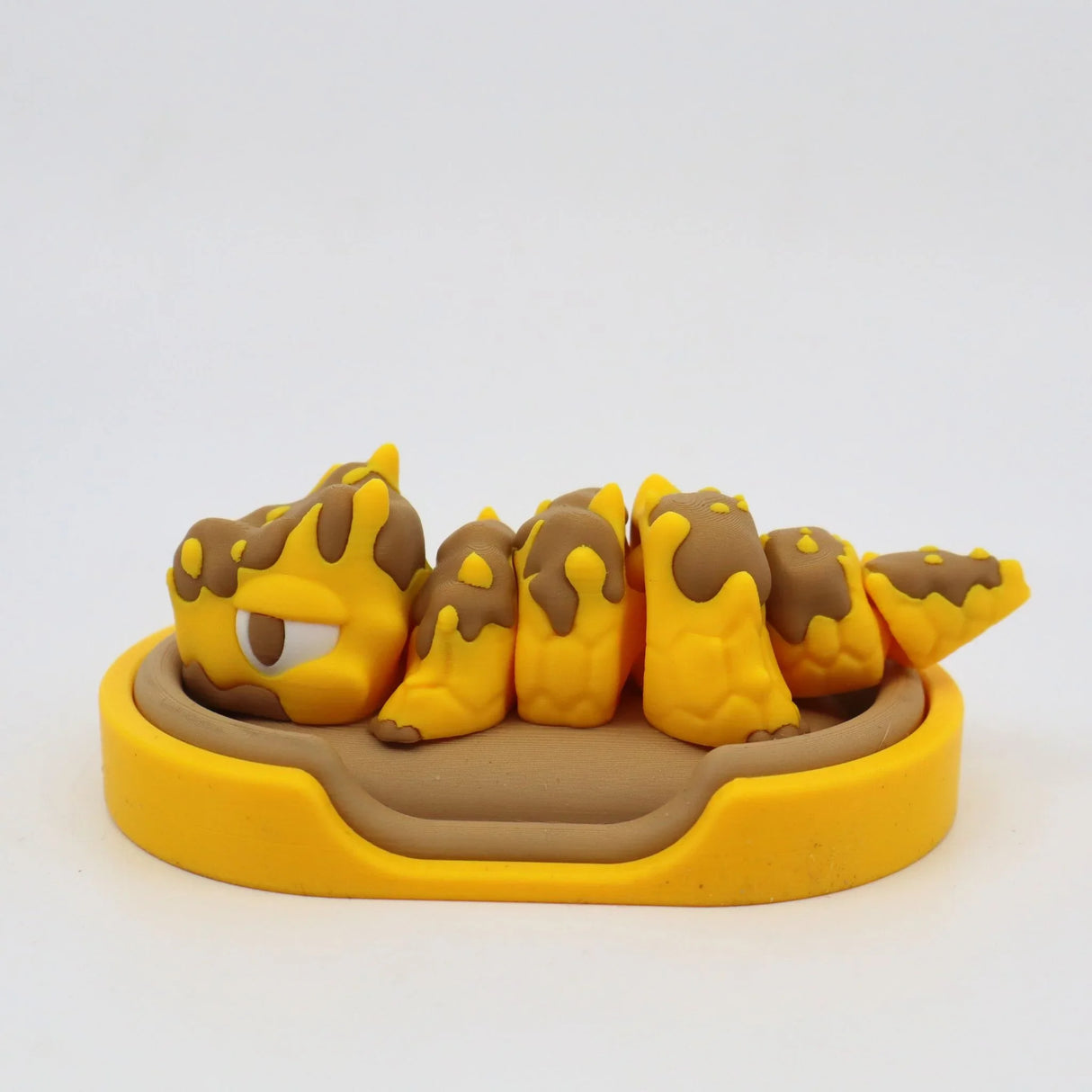 Yellow and brown 3D printed sensory caterpillar toy in a matching tray, for children.