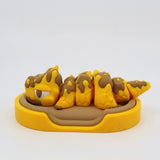 Yellow and brown 3D printed sensory caterpillar toy in a matching tray, for children.