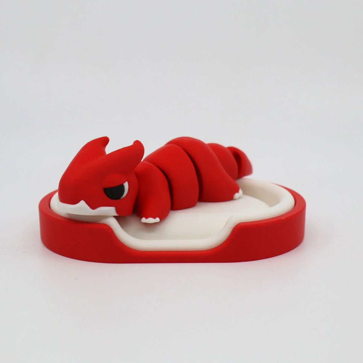 Red articulated dragon sensory toy resting on a white and red tray, 3D printed for kids