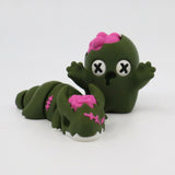 Green zombie-themed sensory toy figures with pink brain details on white background