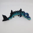 Blue and black articulated barracuda sensory toy with flexible segments on white background