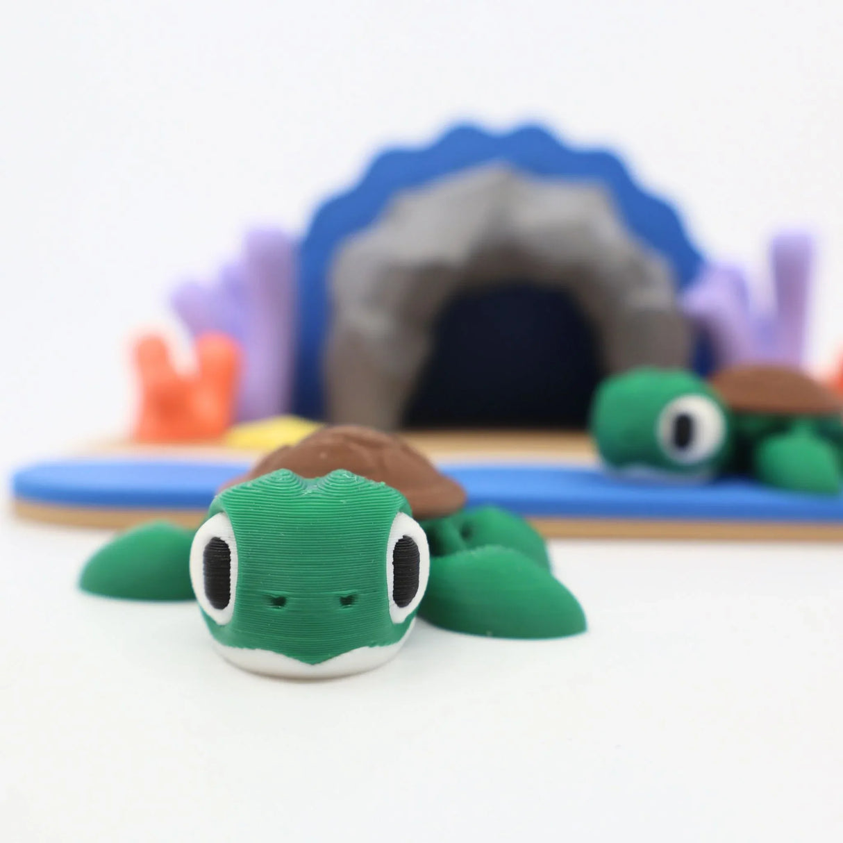 3D printed green turtle sensory toy on beach playset with cave and coral decorations