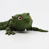 3D printed green bearded dragon sensory toy with red eyes on white background