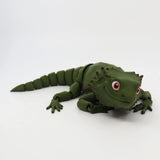 Green 3D printed sensory lizard toy with red eyes on a white background