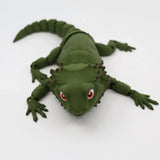 Green 3D printed sensory lizard toy with red eyes on a white background
