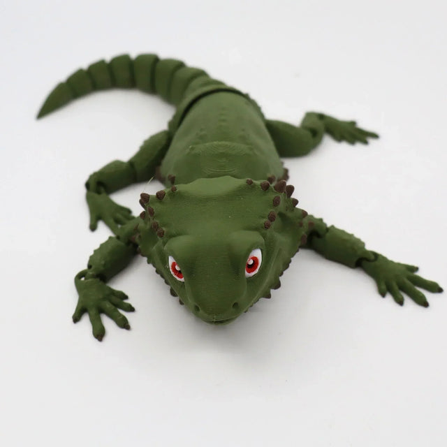 Green 3D printed sensory lizard toy with red eyes on a white background