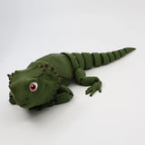 Green 3D printed sensory lizard toy with segmented tail and textured skin on white background.