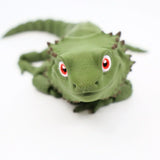 Green 3D printed lizard sensory toy with red eyes on a white background