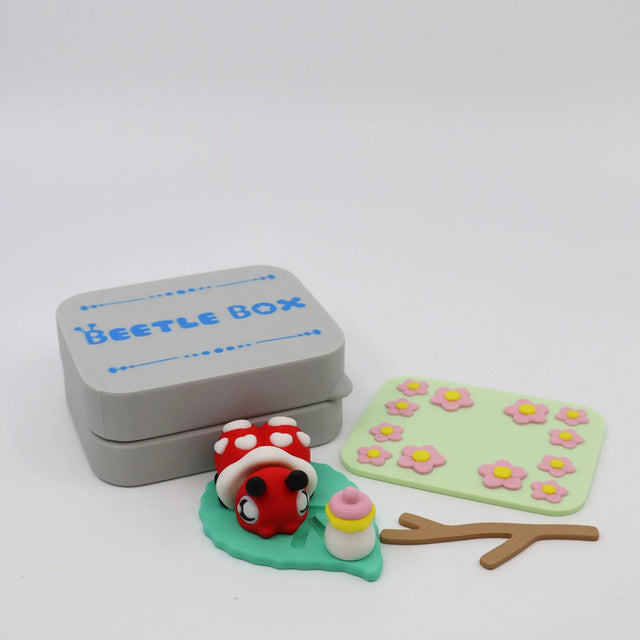 3D printed sensory toy set with ladybug, leaf, flowers, and gray Beetle Box container