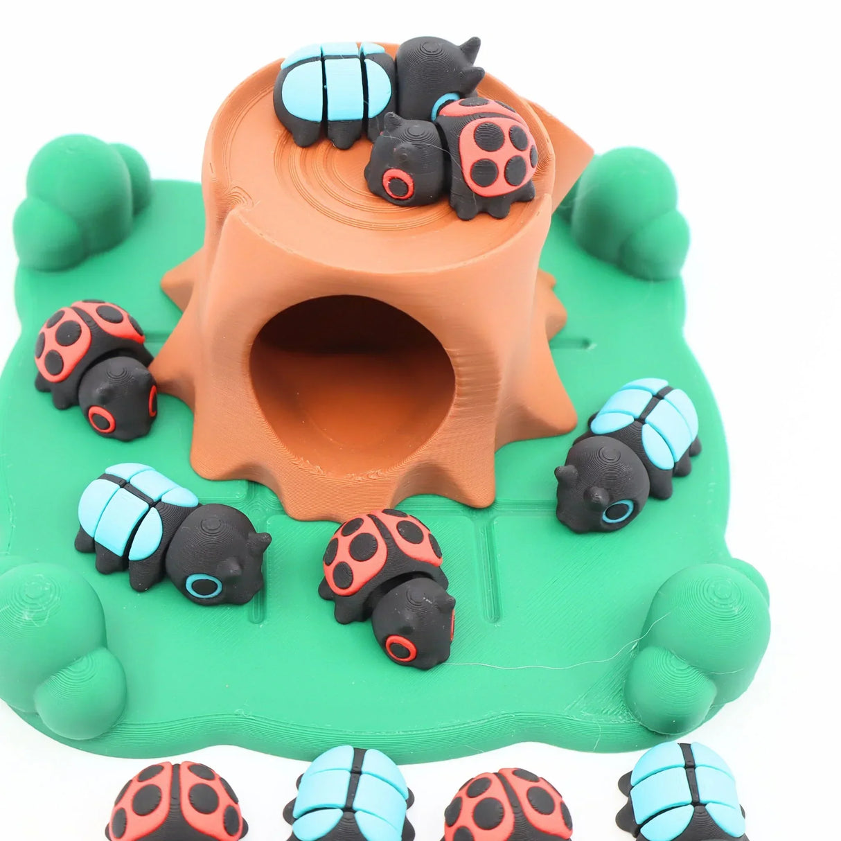 3D printed sensory toy set with colorful ladybugs and tree stump on green base