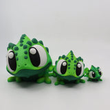 Three green 3D printed chameleon sensory toys with large eyes in different sizes on white background