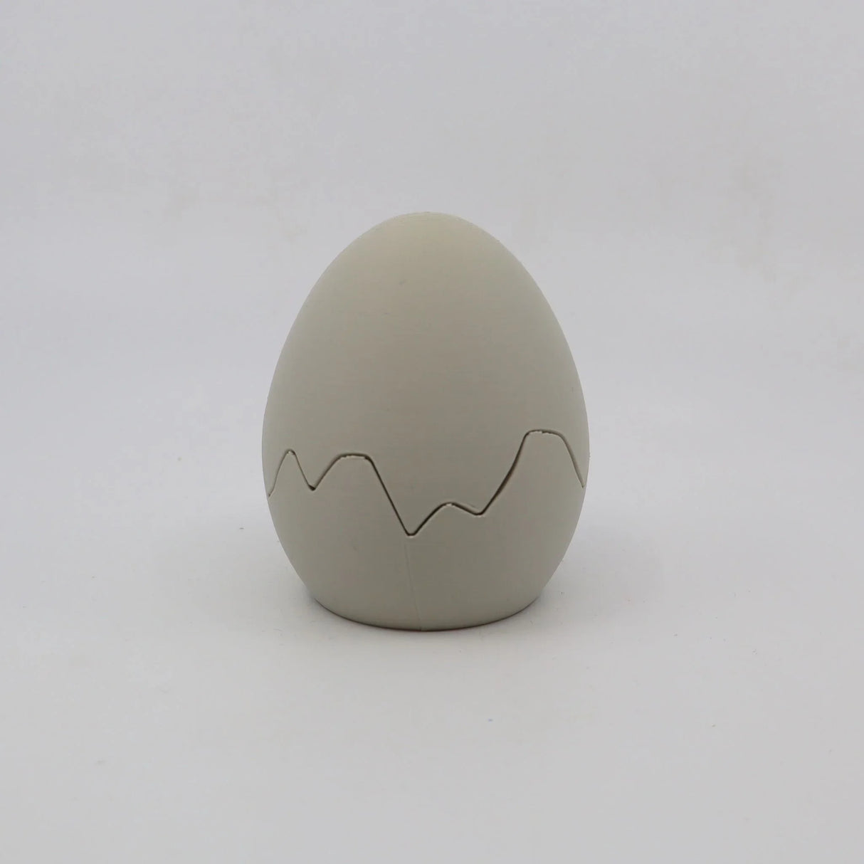 Gray 3D printed sensory egg toy with zigzag crack pattern on white background