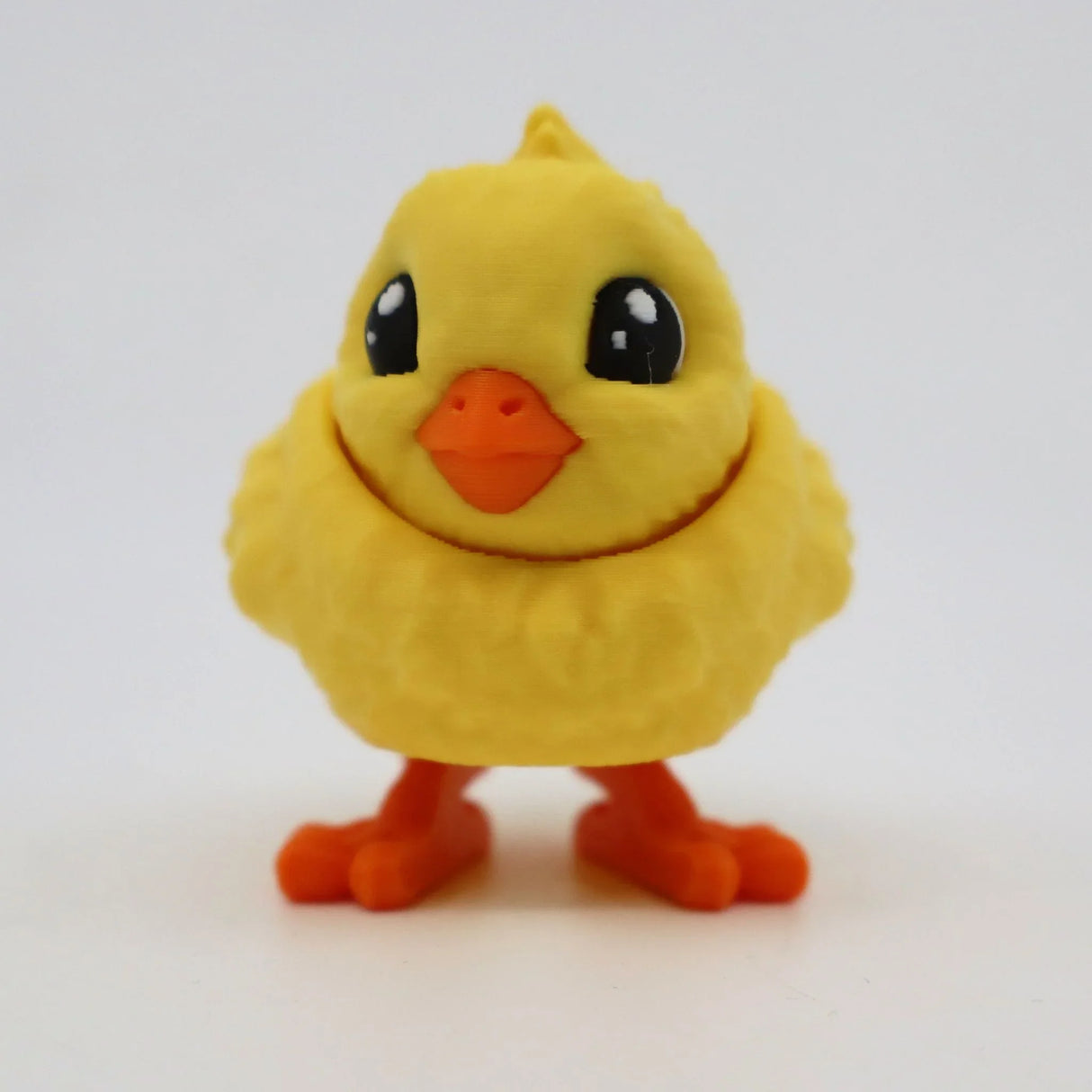 Cute 3D printed yellow chick sensory toy with orange beak and feet on white background.