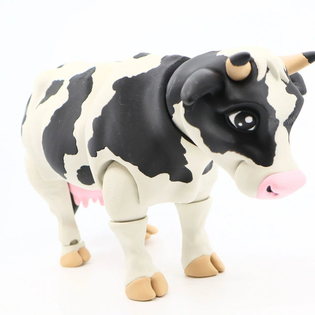 Black and white 3D printed cow sensory toy with pink udder and movable joints