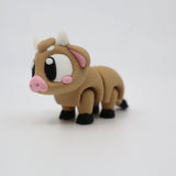 Cute 3D printed cow sensory toy with big eyes, articulated legs, and pastel details on white background