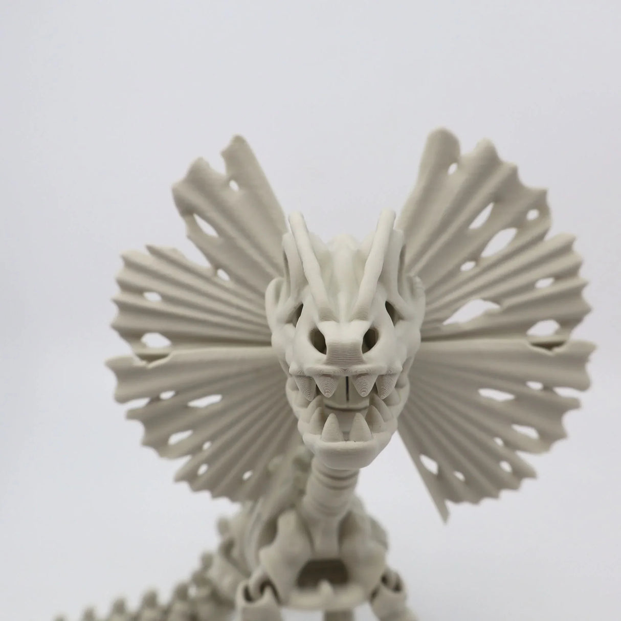 3D printed Dilophosaurus dinosaur sensory toy with frilled neck on white background