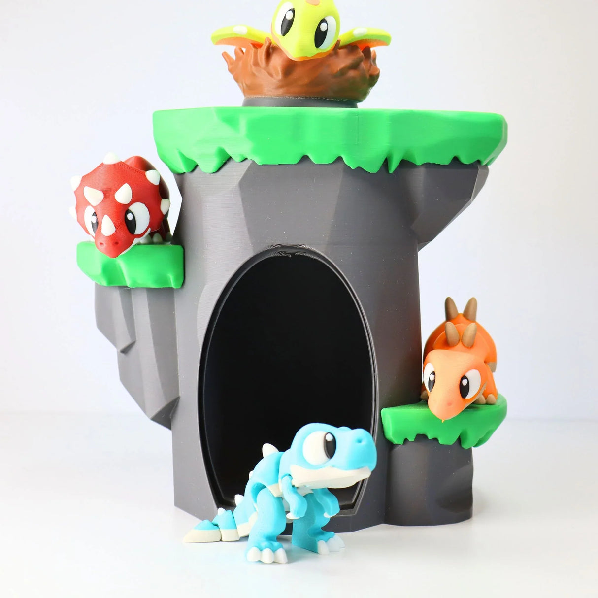 Colorful 3D printed dinosaur sensory toy set on a cave play structure