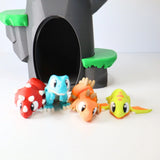 Colorful 3D printed dinosaur sensory toys in front of a toy cave
