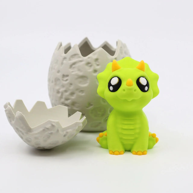 Cute green dinosaur sensory toy sitting beside a cracked 3D printed dinosaur egg