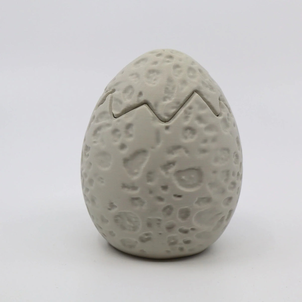 Textured 3D printed dinosaur egg sensory toy with crack detail, light gray color