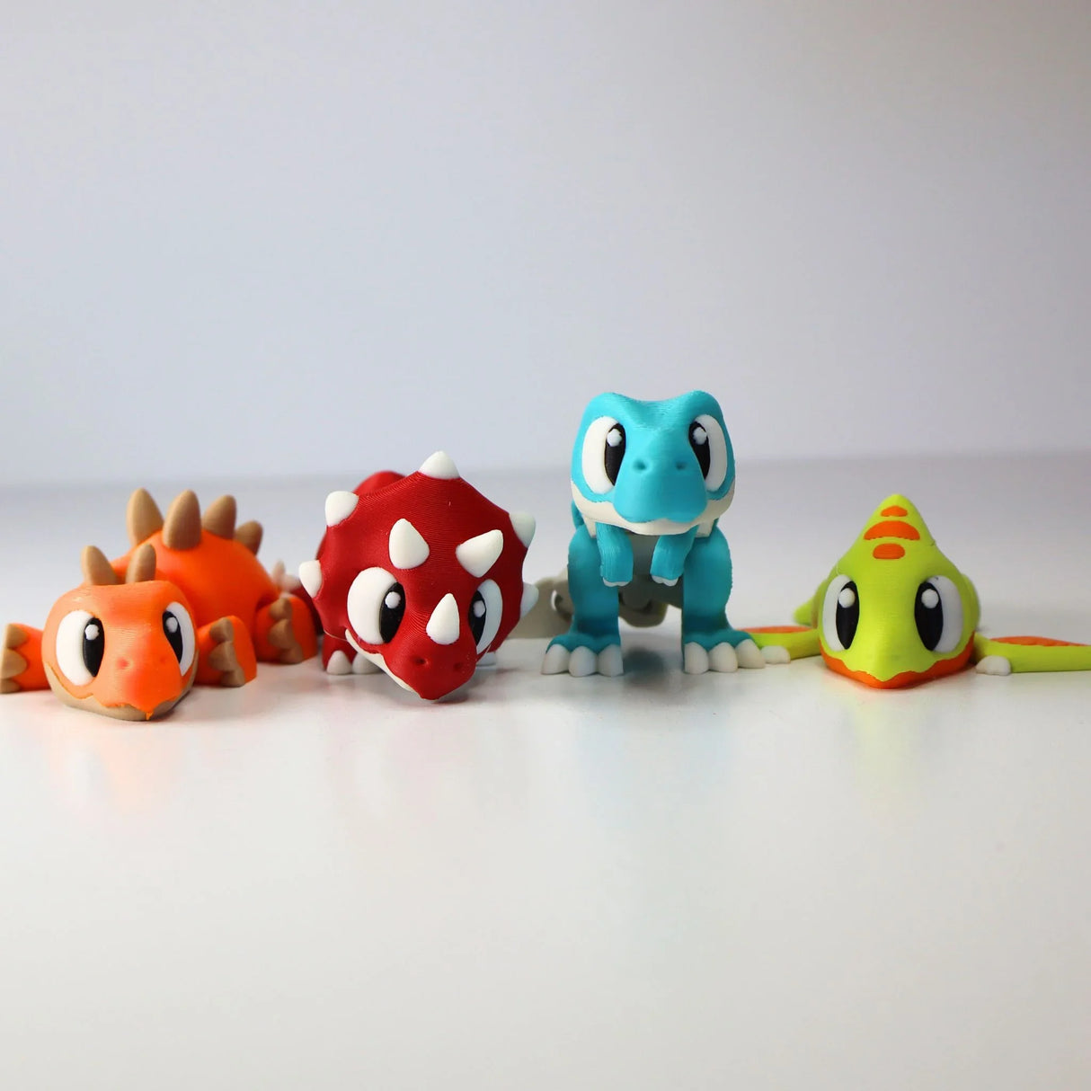 Set of four colorful, 3D printed dinosaur sensory toys for kids on white background