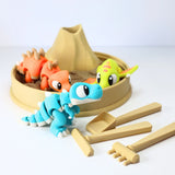 Colorful 3D printed dinosaur sensory toys in a mini sandbox with volcano and toy tools