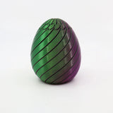 Green and purple 3D printed sensory egg toy with spiral grooves on white background