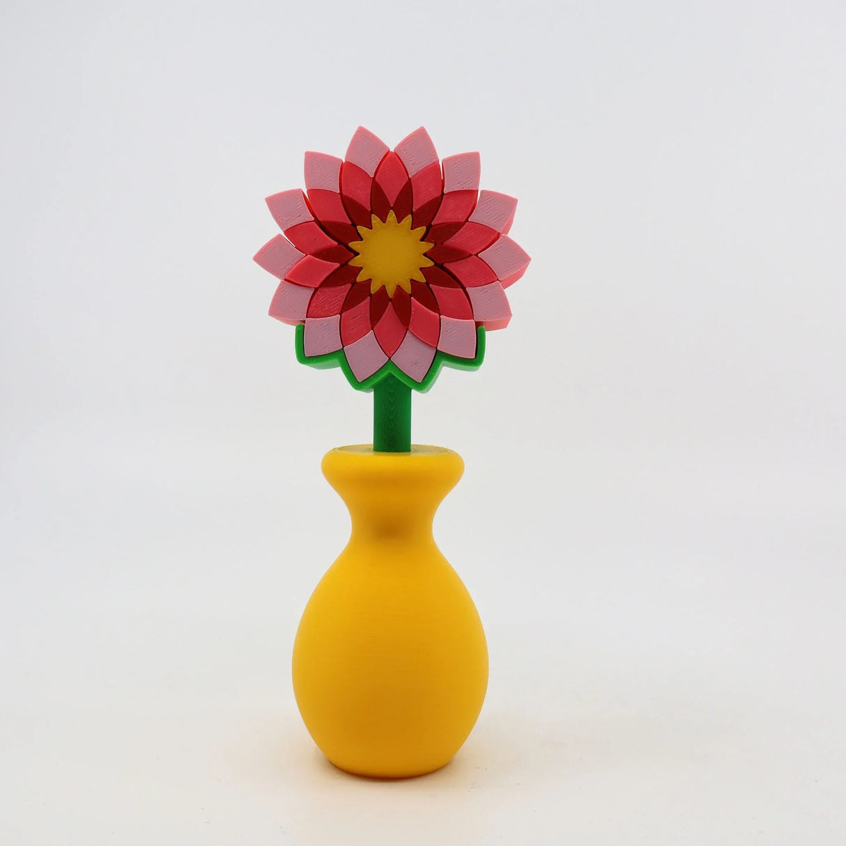 Colorful 3D printed flower sensory toy with pink petals in a yellow vase on white background.