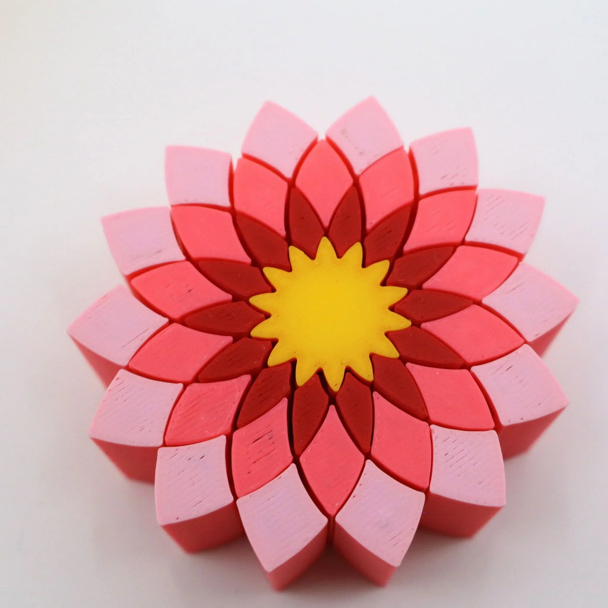 Colorful 3D printed flower puzzle toy with red, pink, and yellow sensory pieces