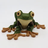 3D printed green and brown frog sensory toy with big eyes on a white background.