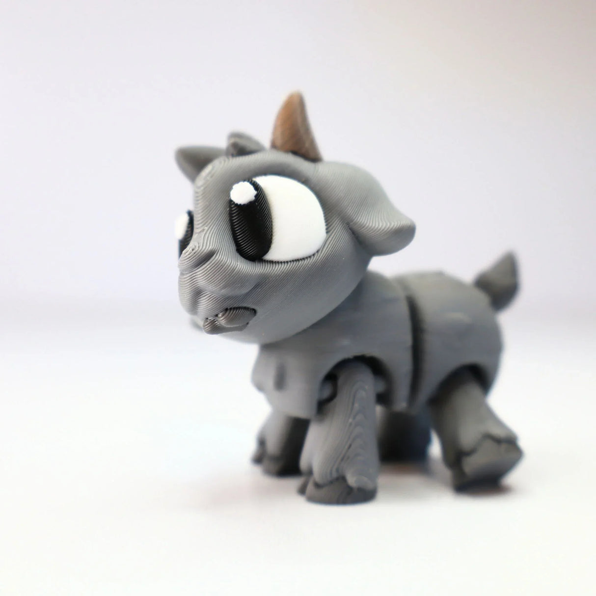 Gray 3D printed goat figurine sensory toy with big eyes on white background
