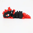 3D printed sensory toy shaped like a black and red dragon with segmented body and large eye