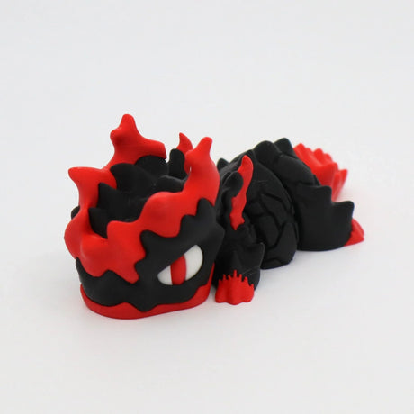 3D printed sensory toy dragon, black and red, with textured scales, on white background
