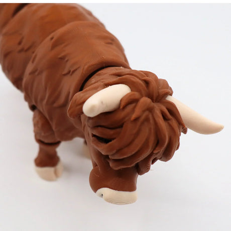 3D printed brown Highland cow sensory toy with white horns on a white background
