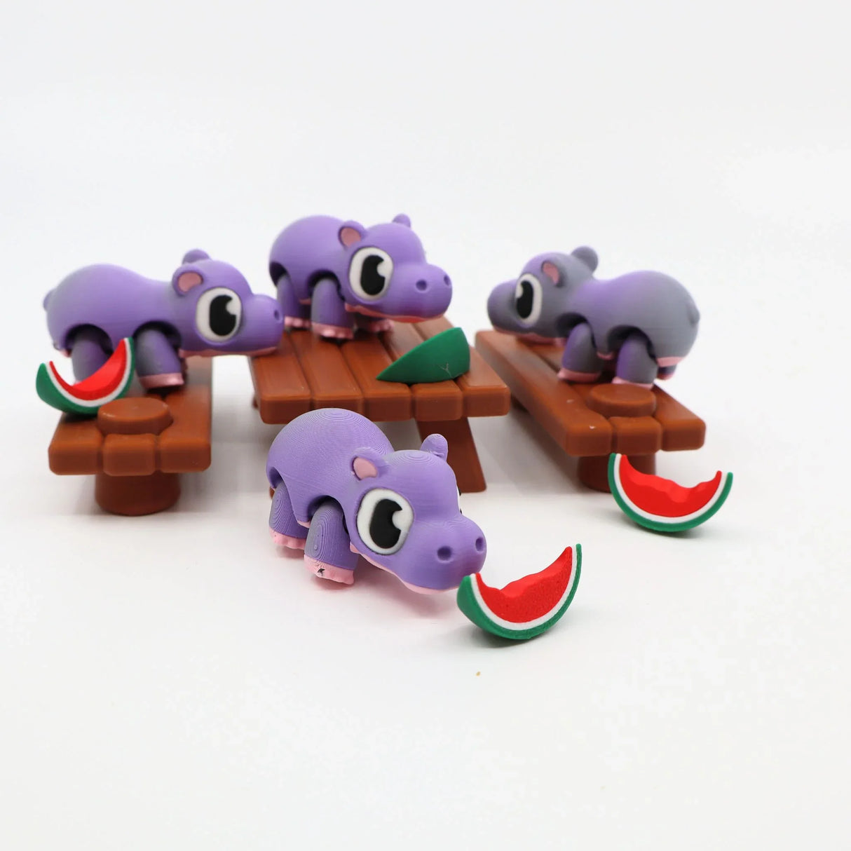 Purple 3D printed hippo sensory toys with watermelon slices on picnic tables