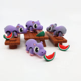 Purple 3D printed hippo sensory toys with watermelon slices on picnic tables