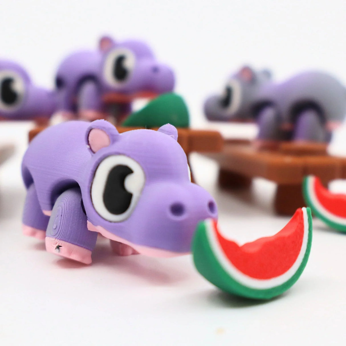 Purple 3D printed hippo sensory toy eating a watermelon slice, playful and colorful design
