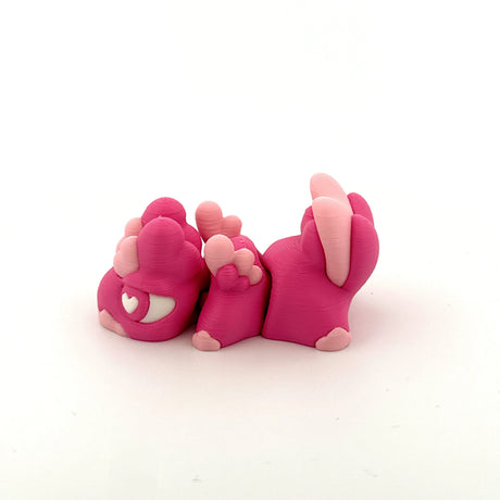 Pink 3D printed sensory toy bunny with heart-shaped eye and paw details on white background