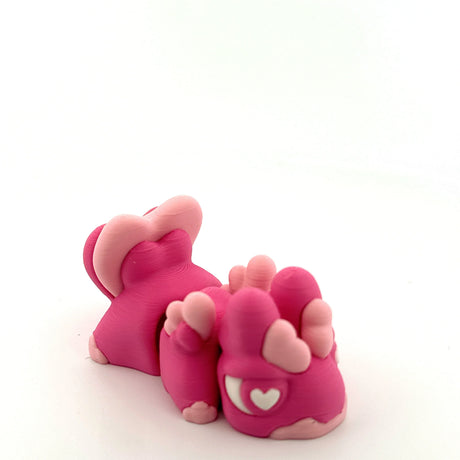 Pink 3D printed sensory toy resembling an animal with heart and paw details on white background