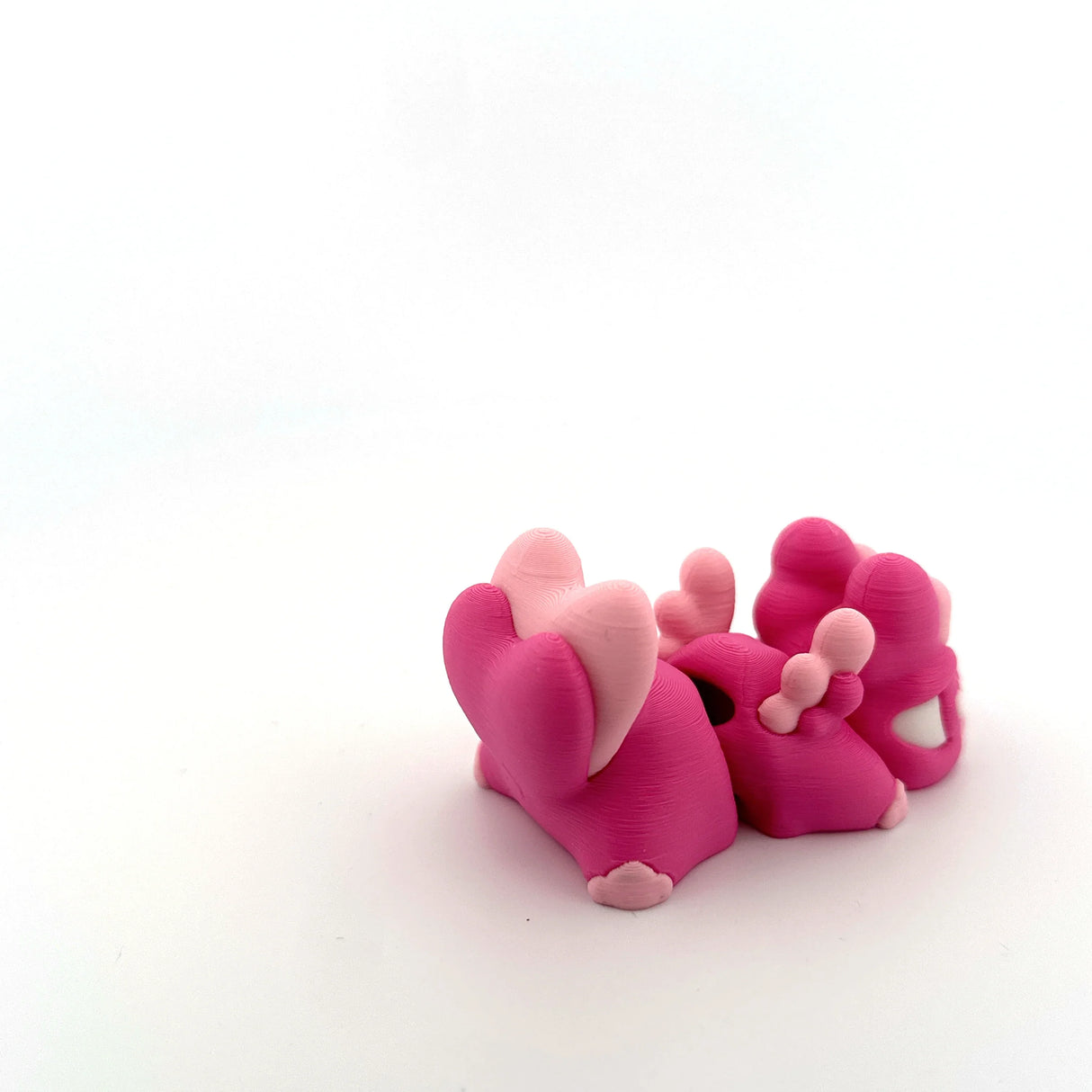 Pink 3D printed sensory toy figures with animal shapes on white background
