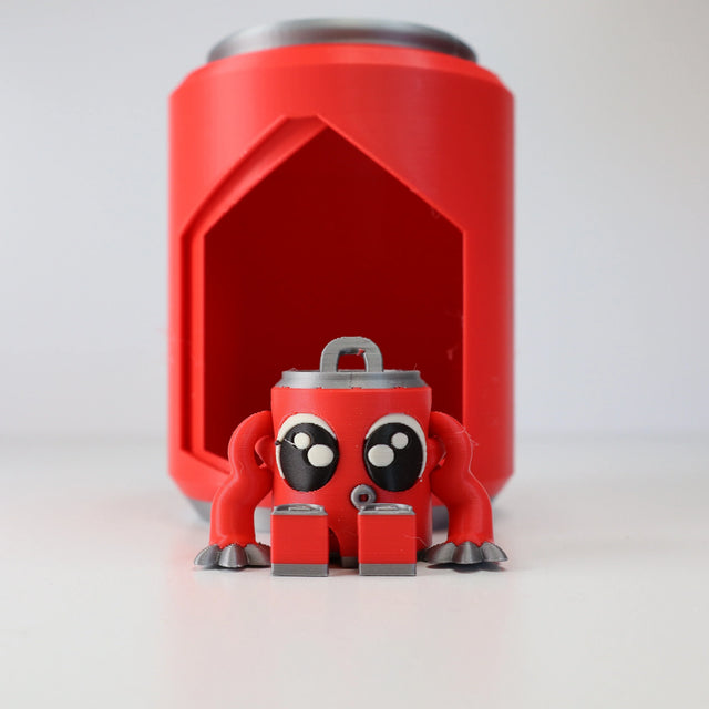 3D printed red sensory toy can with cute eyes and arms in front of matching holder