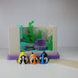 Colorful 3D printed fish sensory toys in front of a mini aquarium playset with plants and rocks