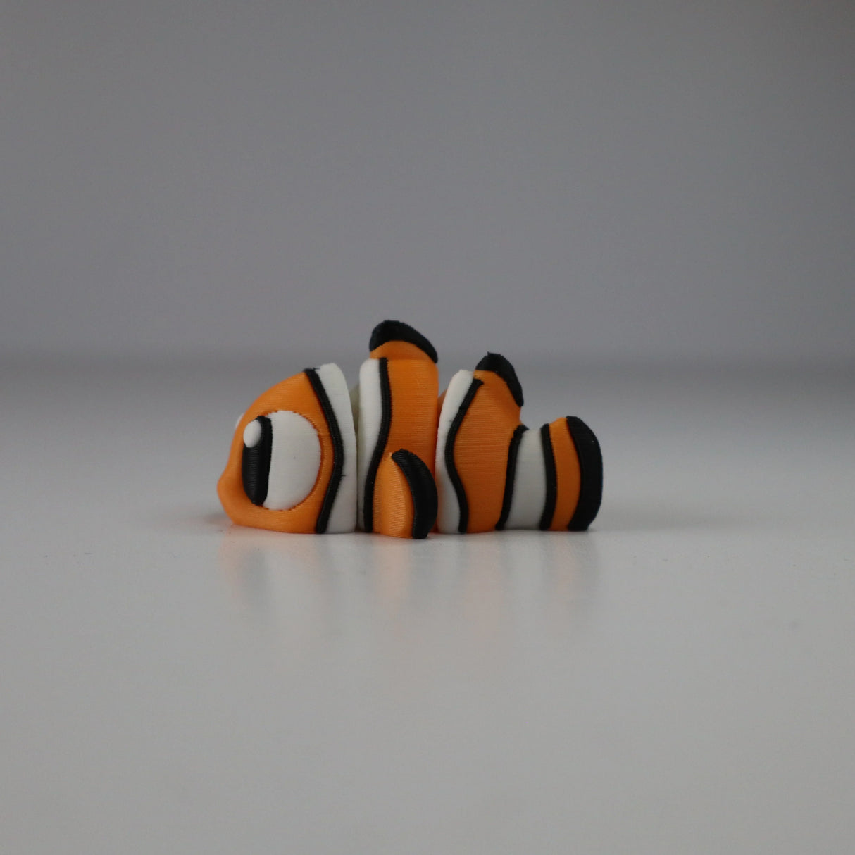 3D printed orange and white clownfish sensory toy on a plain white background