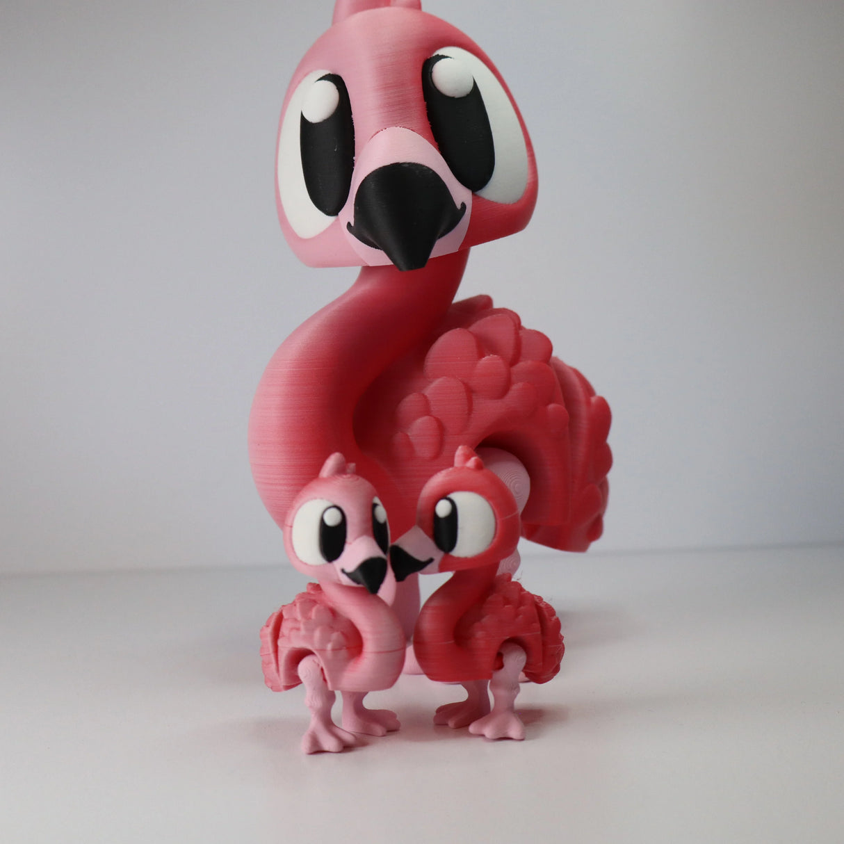 3D printed pink flamingo sensory toys, one large and two small, on white background