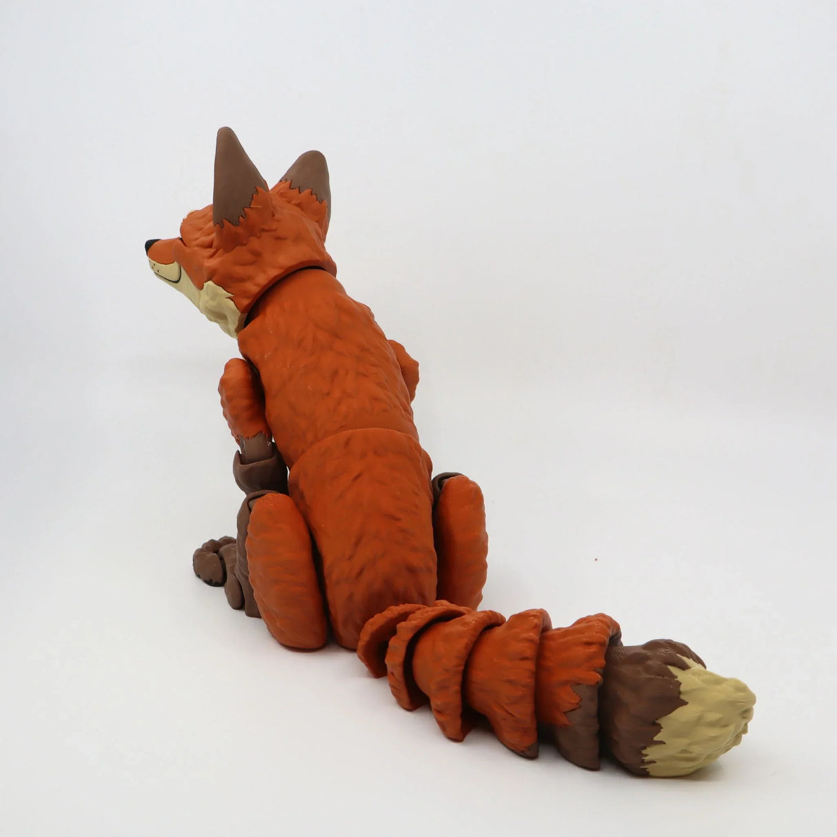 3D printed orange fox sensory toy with flexible tail on a white background